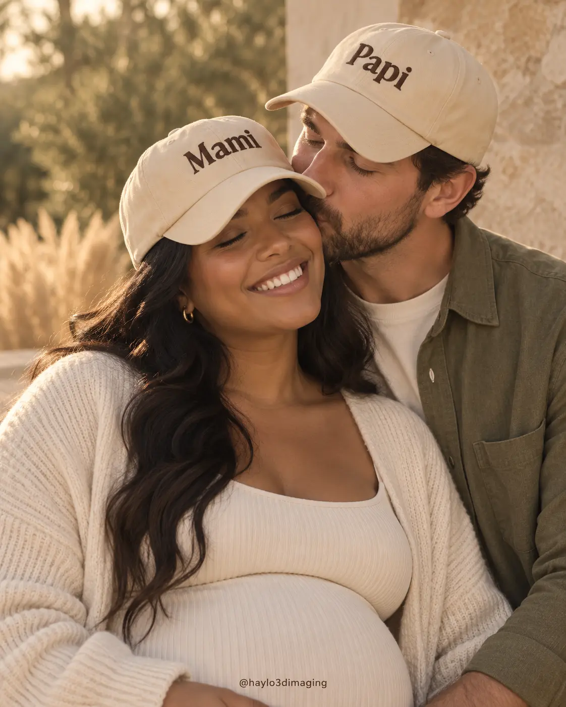 Expectant parents wearing embroidered Mami and Papi hats at golden hour